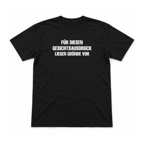 Für diesen Gesichtsausdruck liegen Gründe vor – Unisex T-Shirt – Black – Flat-Lay Vorderseite (Mockup)